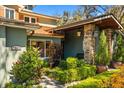 Charming home entrance with stone accents, lush landscaping, and a covered porch area with bench at 7849 Georgeann St, Winter Park, FL 32792