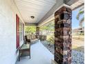 Cozy front porch featuring stone column accents, neutral furniture, and a quaint sitting area at 104 Bentley Oaks Blvd, Auburndale, FL 33823