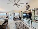 Modern living room featuring tile flooring, statement ceiling fan, and mirrored shelving units at 104 Bentley Oaks Blvd, Auburndale, FL 33823