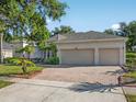 Well-maintained home with a three-car garage and a brick-paved driveway surrounded by mature trees at 1551 Sherbrook Dr, Clermont, FL 34711
