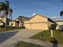 Beige home with a three-car garage and well-maintained landscaping at 2715 Bartlet Dr, Kissimmee, FL 34741
