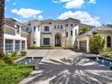 Elegant home featuring a paver driveway with water features, arched entry, and multiple garage bays at 6137 Grosvenor Shore Dr, Windermere, FL 34786
