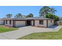 Well-maintained single-story house with mature trees, featuring a spacious driveway leading to the garage at 5828 Westport Dr, Port Orange, FL 32127