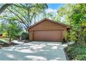 A spacious two-car garage is set back from the street, surrounded by lush greenery and mature trees at 1 W Village Dr, Oviedo, FL 32765