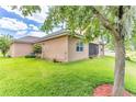 View of the rear of a tan home with lush green lawn, large shade tree, and covered patio at 2724 Westyn Cove Ln, Ocoee, FL 34761