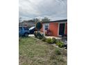 A single-story home featuring a quaint front yard with lush greenery and a vibrant orange exterior at 330 S Buena Vista Ave, Orlando, FL 32835