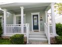 Inviting front porch with classic white columns, stylish blue door, and manicured landscaping at 351 Lansbrook Ln, Winter Springs, FL 32708