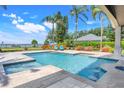 An inviting pool area with a built-in bar and comfortable lounge chairs overlooking the tranquil lake at 3640 Crump Rd, Winter Haven, FL 33881