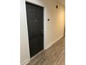 Hallway view of unit entry door, featuring wood-look laminate floors and neutral wall colors at 5550 E Michigan St # 2202, Orlando, FL 32822