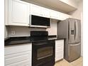 Functional kitchen featuring white cabinetry, black appliances, and sleek countertops for convenient meal preparation at 5578 Metrowest Blvd # 10, Orlando, FL 32811