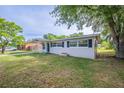 Single-story home with a well-manicured lawn, covered parking, and black window shutters at 73 Channing Ave, Orlando, FL 32811