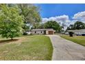 Exterior view of a well-manicured lawn, a long driveway, and mature trees surrounding the property at 1179 Shadow Run Dr, Lakeland, FL 33813