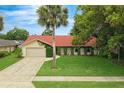 Inviting single-story home featuring a red roof and lush green lawn with a palm tree at 222 Yarmouth Rd, Fern Park, FL 32730