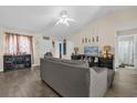 Spacious living room with a gray sectional sofa, modern ceiling fan, bar, and access to the bathroom at 335 Snook Way, Poinciana, FL 34759
