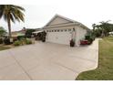 View of the home's exterior, featuring a spacious driveway, a two-car garage, and a well-manicured lawn at 1669 Plum Branch Ter, The Villages, FL 32162