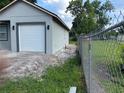 Side view of a gray house with a one-car garage and a chain-link fence along the property line at 2451 W 18Th St, Sanford, FL 32771