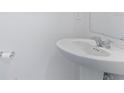 A pedestal sink in a powder room, showcasing simplicity and functionality with a toilet paper holder at 1179 Tyler Loop, Winter Haven, FL 33884