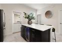 Kitchen island featuring a wine cooler, black cabinetry, and white countertop with seating at 12180 Sonnet Ave, Orlando, FL 32832