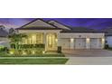 Home exterior featuring illuminated landscaping, garage, and holiday lighting at dusk at 13202 Spring Grove Way, Winter Garden, FL 34787