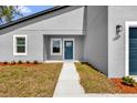 Close-up of a modern home's entrance featuring a blue door, white trim, and manicured landscaping at 13673 Sw 43 Cir, Ocala, FL 34473