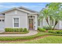 Inviting entryway showcasing a wood front door with decorative wreath, framed by trimmed hedges and a brick walkway at 1633 Pine Ave, Winter Park, FL 32789
