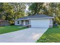 Single-story home with two car garage featuring a concrete driveway and well manicured lawn at 57 Pine Trace Crse, Ocala, FL 34472