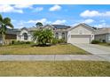 Beautifully landscaped home with lush lawn, mature palm, and a paved driveway to the two-car garage at 625 Waterland Ct, Orlando, FL 32828