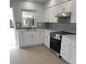 Modern kitchen with white cabinetry, stainless steel appliances, and stylish backsplash at 769 Avenue Q Se, Winter Haven, FL 33880