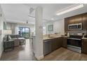 A modern kitchen open to the living area with stainless steel appliances and wood grain floors at 14501 Grove Resort Ave # 3735, Winter Garden, FL 34787