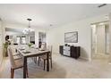 Bright dining room with modern chandelier, table set for service, and elegant accent cabinet at 14717 Royal Poinciana Dr, Orlando, FL 32828
