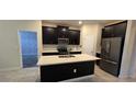 Modern kitchen features dark cabinetry, stainless steel appliances, and a center island with a sink at 3043 Beaver Creek Dr, Kissimmee, FL 34746