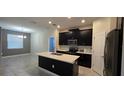 Modern kitchen features dark cabinetry, stainless steel appliances, and a center island with a sink at 3043 Beaver Creek Dr, Kissimmee, FL 34746