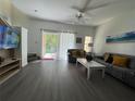 Cozy living room featuring modern gray flooring, ceiling fan, and sliding glass doors to outdoor space at 1119 Park Ridge Cir, Kissimmee, FL 34746