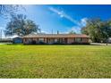 Charming single-story brick home with a well-manicured lawn and mature trees against a bright blue sky at 1624 Bel Air Ave, Orlando, FL 32812