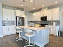 Bright kitchen features white cabinetry, stainless steel appliances, center island with bar seating, and wood-look flooring at 2445 Verde View Dr, Apopka, FL 32703