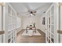 Bright home office featuring glass French doors, modern desk, and ceiling fan at 3666 Maidencain St, Clermont, FL 34714