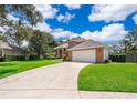 Brick home exterior with driveway leading to an attached two car garage and a lush manicured lawn at 5479 Baytowne Pl, Oviedo, FL 32765