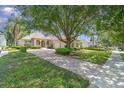 Paver driveway leading to a well-maintained home with mature trees, lush landscaping, and a welcoming facade at 6125 Foxfield Ct, Windermere, FL 34786