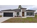 Charming single-story home featuring a dark garage door, orange front door, and freshly installed landscaping at 699 Marion Oaks Trl, Ocala, FL 34473
