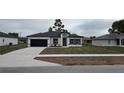 Charming single-story home featuring a dark garage door, orange front door, and freshly installed landscaping at 699 Marion Oaks Trl, Ocala, FL 34473