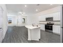 Bright, open kitchen featuring granite countertops, stainless steel appliances, and modern gray wood-look floors at 914 Poppy Ln, Dundee, FL 33838