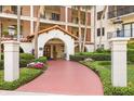 Inviting building entrance with manicured landscaping, a red walkway, and an arched entryway, blending nature and architecture at 100 S Interlachen Ave # 107F, Winter Park, FL 32789