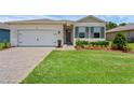 Single-story home with brick paver driveway, two-car garage and a freshly landscaped front yard at 1511 Lyonsdale Ln, Sanford, FL 32771