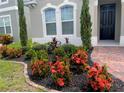 Lush landscaping featuring vibrant red flowers and manicured greenery surrounds the entrance of this lovely home at 256 Whirlaway Dr, Davenport, FL 33837