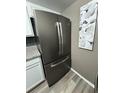 Close-up of a stainless steel, french-door refrigerator against a neutral wall with art in an updated kitchen at 1001 Plantation Dr # A2, Kissimmee, FL 34741