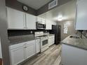 A modern kitchen with white cabinets, stainless steel appliances, granite countertops, and a stylish backsplash at 1001 Plantation Dr # A2, Kissimmee, FL 34741
