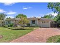 Charming single-story home with brick driveway and lush landscaping, set against a clear blue sky at 1440 Roosevelt St, Orlando, FL 32804