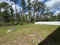Spacious backyard featuring a fire pit area, framed by tall trees and a white vinyl fence at 1476 11Th Ave, Deland, FL 32724