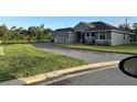Beautiful gray house with stone accents, a paved driveway, and a lush green lawn at 1504 Cordgrass Way, Lakeland, FL 33813