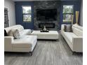 Modern living room with a fireplace, stylish white sofas, gray wood-look floors, and lots of natural light at 1504 Cordgrass Way, Lakeland, FL 33813